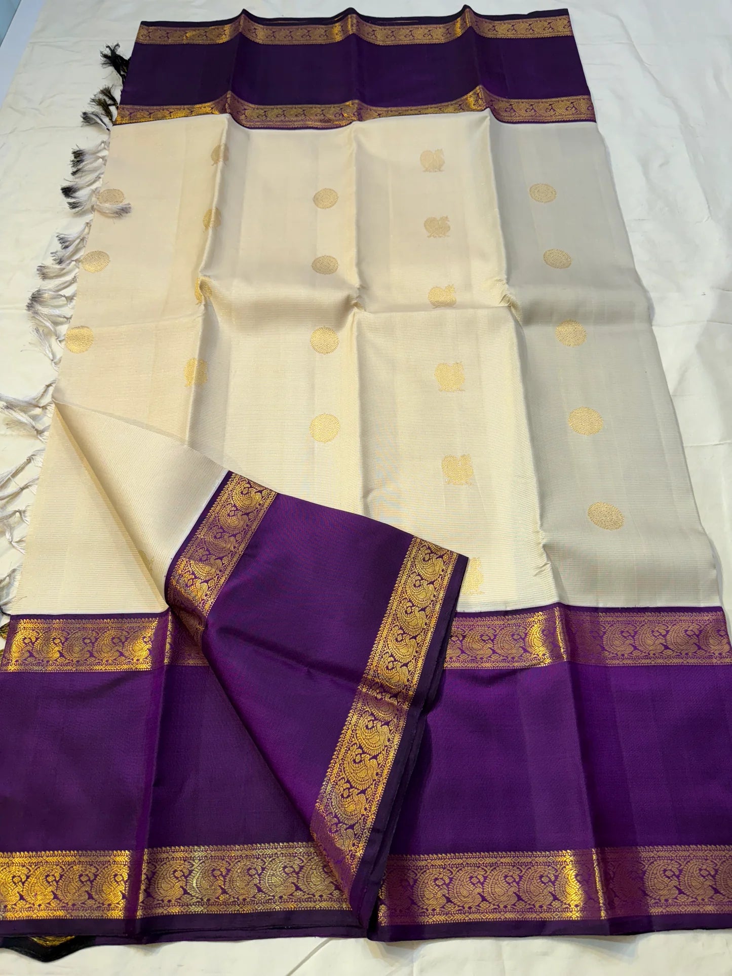 Ivory Violet Vairaoosi — Pure Silk Kanchipuram Saree
Pearl-Ivory Vairaoosi Body with Gold Round Buttas ✨
Deep Violet Korvai Border & Chevron Zari Pallu • Silk Mark Certified • Free USA Shipping • ships in 2 weeks