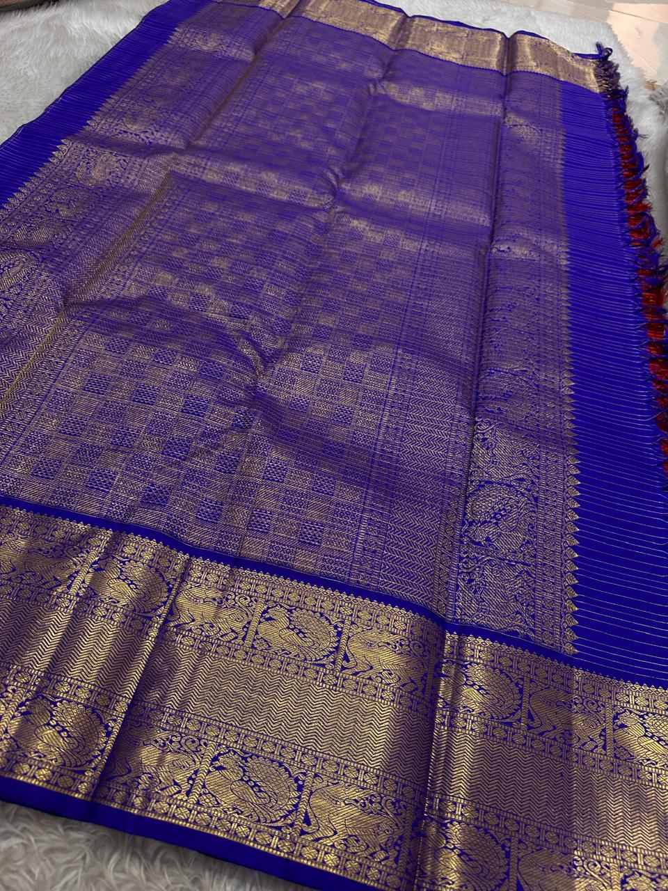 Raaga – Red and Blue Pure Kanchipuram Silk Saree with Gold Zari Border
Features a striped red body with small gold buttas and a royal blue pallu.
Finished with intricately woven peacock motifs in pure zari across the border.