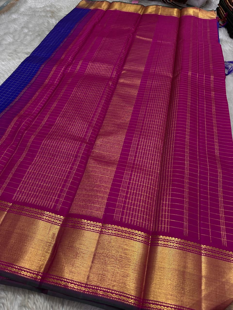 Sapphire Zari Kattam – Pure Kanchipuram Silk Saree
Brilliant Sapphire Blue Body with Gold Zari Checks
Broad Golden Border with Magenta Highlights & Temple Motifs
Royal Magenta Pallu with Lustrous Zari Stripes
Silk Mark Certified, delivery in 2 weeks
