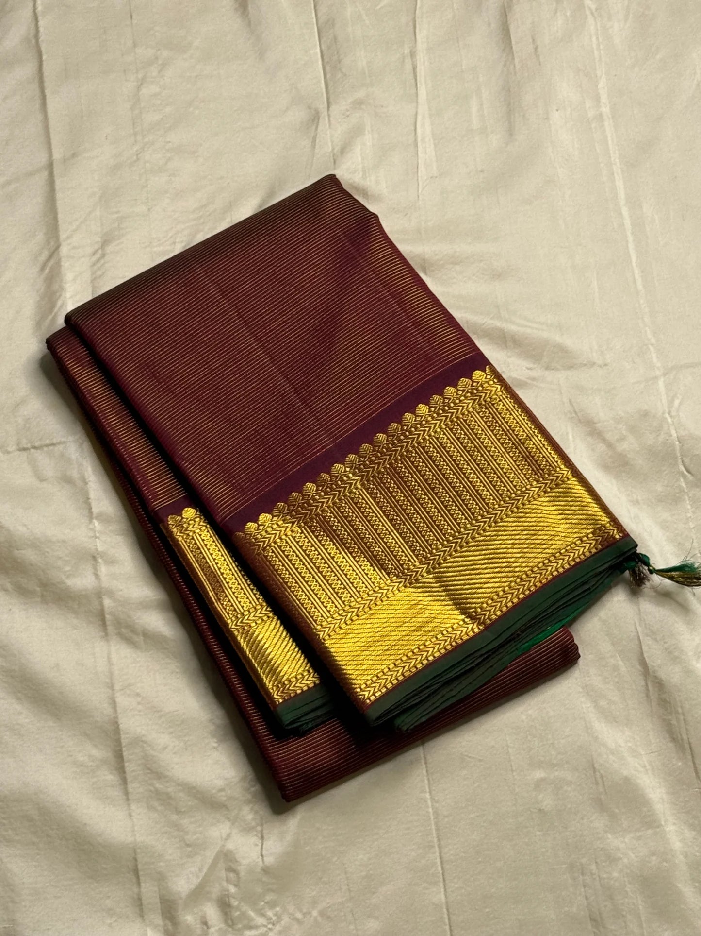 Shyama Vairaoosi — Pure Silk Kanchipuram
Deep Shyama brown with micro Vairaoosi pinstripes
Temple-column antique gold zari border, bottle-green selvedge
 Grand striped zari pallu with hand-tied tassels
Silk Mark Certified • free shipping