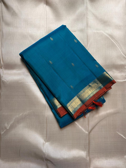 Peacock Teal Ilai Butta – serene teal body with copper-gold zari borders
Pure Kanchipuram silk • dainty leaf (ilai) buttas scattered across the body
Rich teal zari pallu
Silk Mark Certified | Fall & Pico Done | Blouse Stitching Available ($30)
