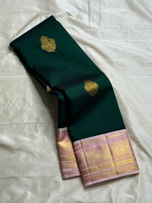 Rose-Tipped Emerald – Korvai Kanchipuram Pure Silk Saree
Emerald green body with zari paisley buttas
Blush-pink korvai border with muthuseer coin rows & vine motifs
Blush-pink zari-brocade pallu with elegant stripe details
Contrast blush blouse silk mark