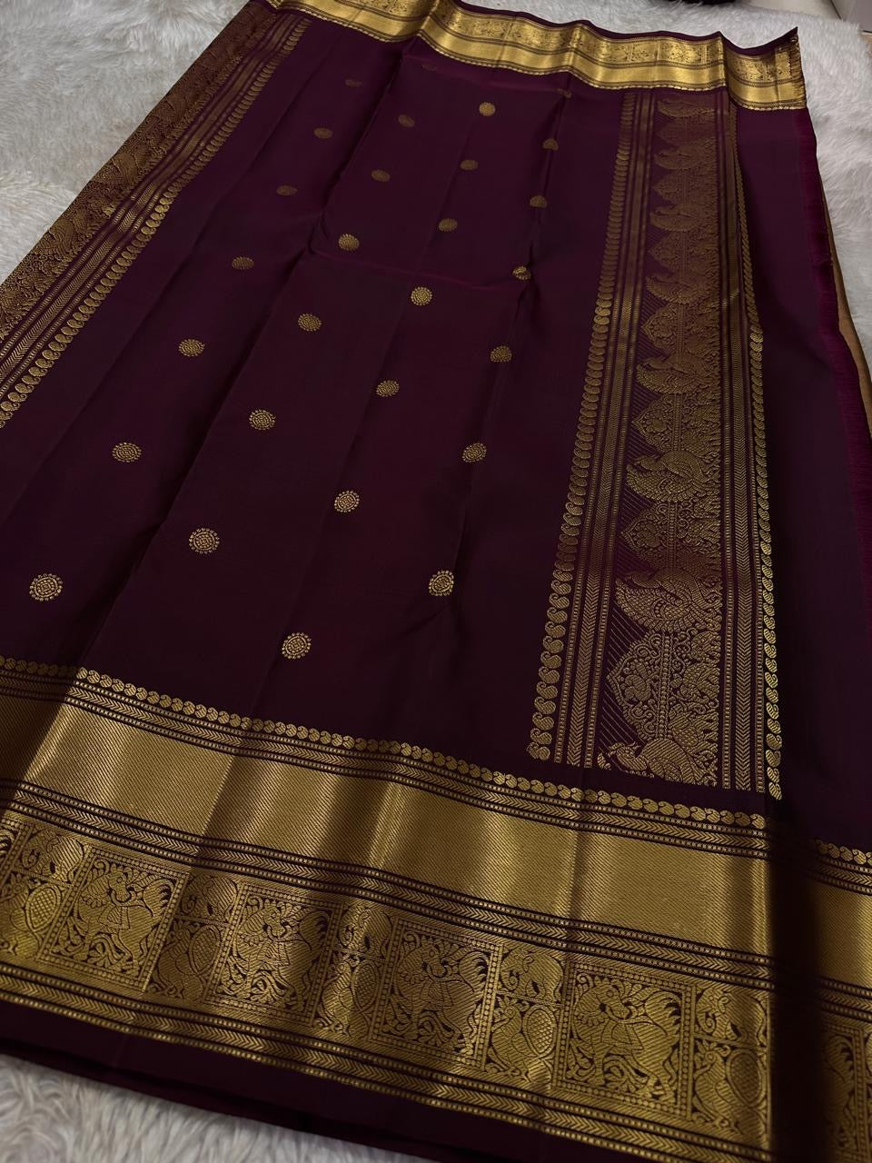 Pari is a graceful Kanchipuram pure silk saree in a serene copper-rose gold brown hue. Scattered peacock zari buttas . Framed by an antique-gold korvai border temple-inspired yali, annam, and floral medallions, finished with a deep wine-maroon Pallu