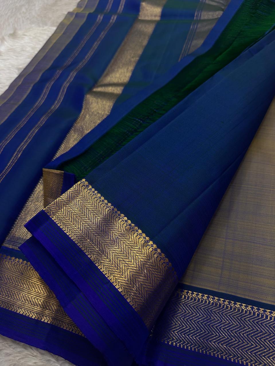 Varnam – Dove Tail Gray & Peacock Blue Kanchipuram Silk Saree. Featuring rich gold paisley buttas, a bold chevron zari border, and pure handloom silk craftsmanship ✨ Silk Mark Certified | Blouse Stitching Available | Free USA Shipping