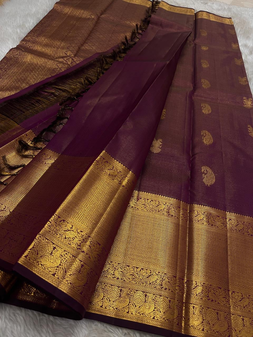 Varnika – Handwoven Kanchipuram Silk Saree in Plum Wine
A regal plum Kanchipuram silk saree adorned with gold zari paisleys and Gandaberunda motifs