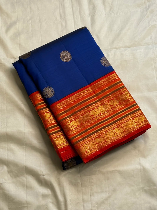 Royal blue silk saree close-up showing circular coin buttas and rich red-gold zari border