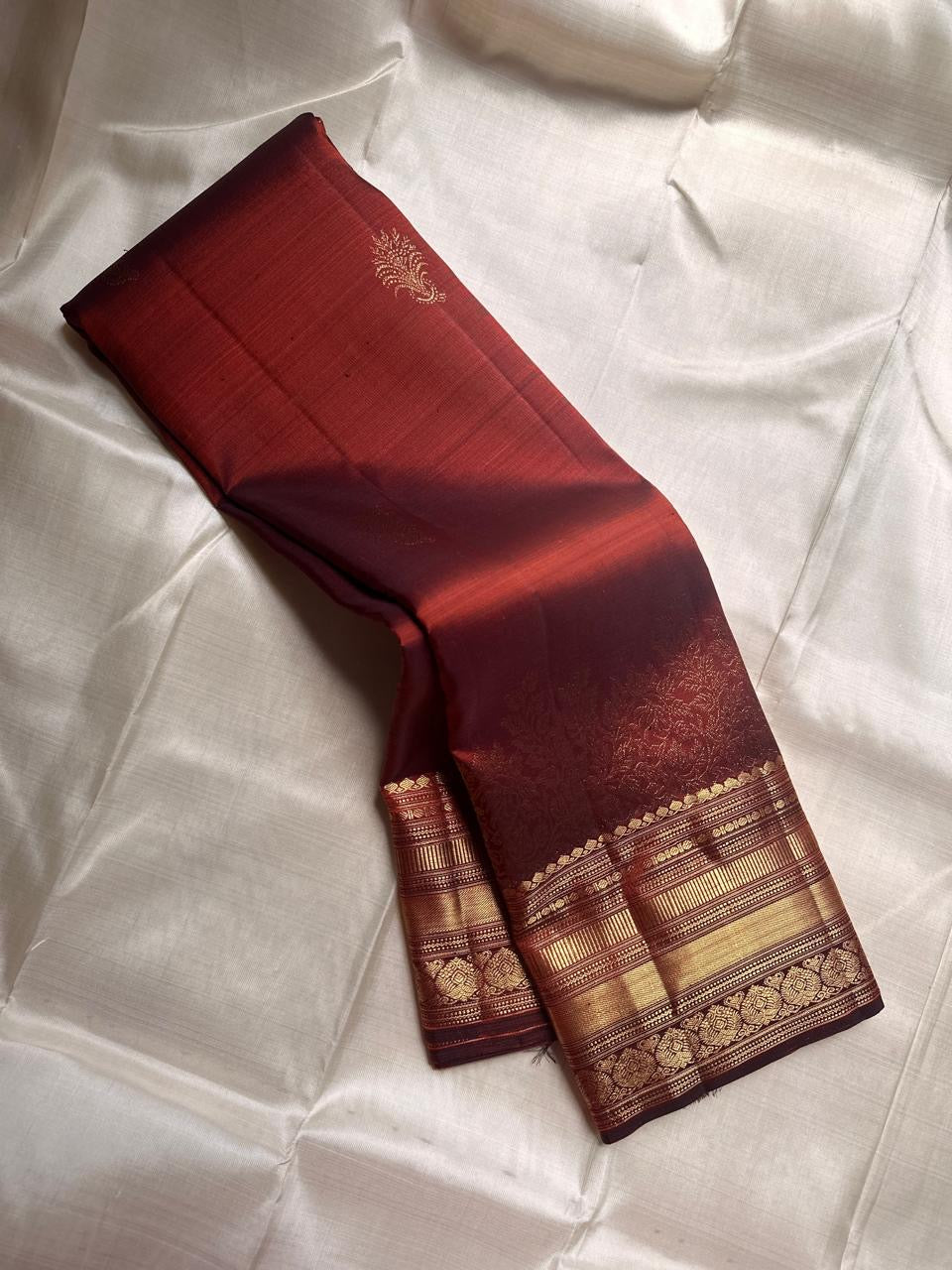 Gilded Rust – Pure Kanchipuram Silk Saree
Deep rust body with delicate paisley zari buttas 🌿
Antique-gold border featuring kaddi stripes & floral motifs ✨
Grand brocade pallu with lattice jaal & floral vines 🕊️
Silk Mark Certified, delivery in 2 weeks