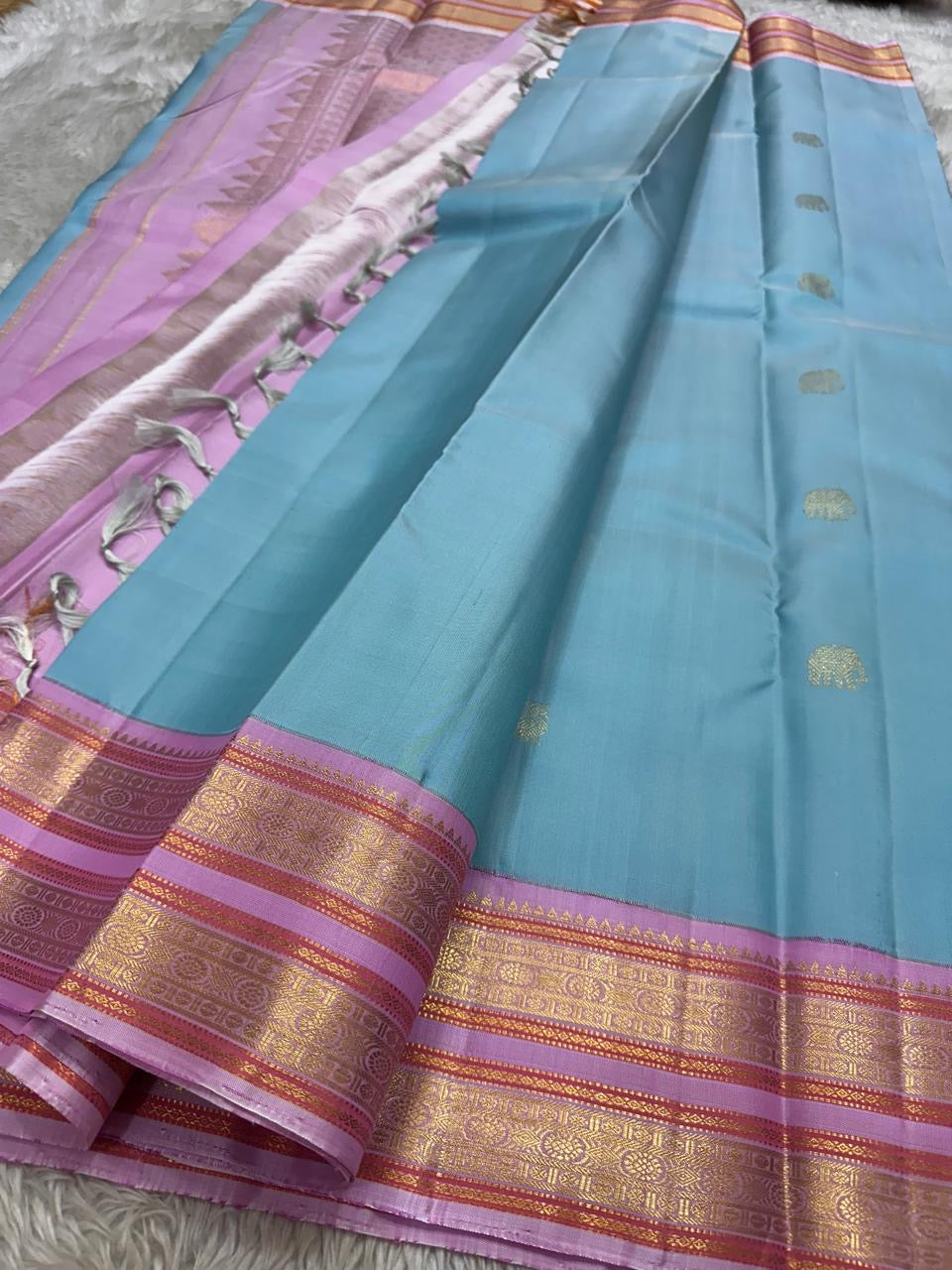 Nirvi – Sky Blue & Purple Kanchipuram Pure Silk Saree with Mayil & Yanai Zari Motifs
Graceful Harmony of Peacock & Elephant Motifs on Soothing Blue
Handwoven Elegance with Traditional Rettapet Border & Rich Zari Detailing