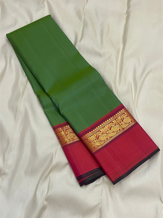 Green silk saree folded lengthwise showing a pink border with gold zari woven pattern and dark edge piping.