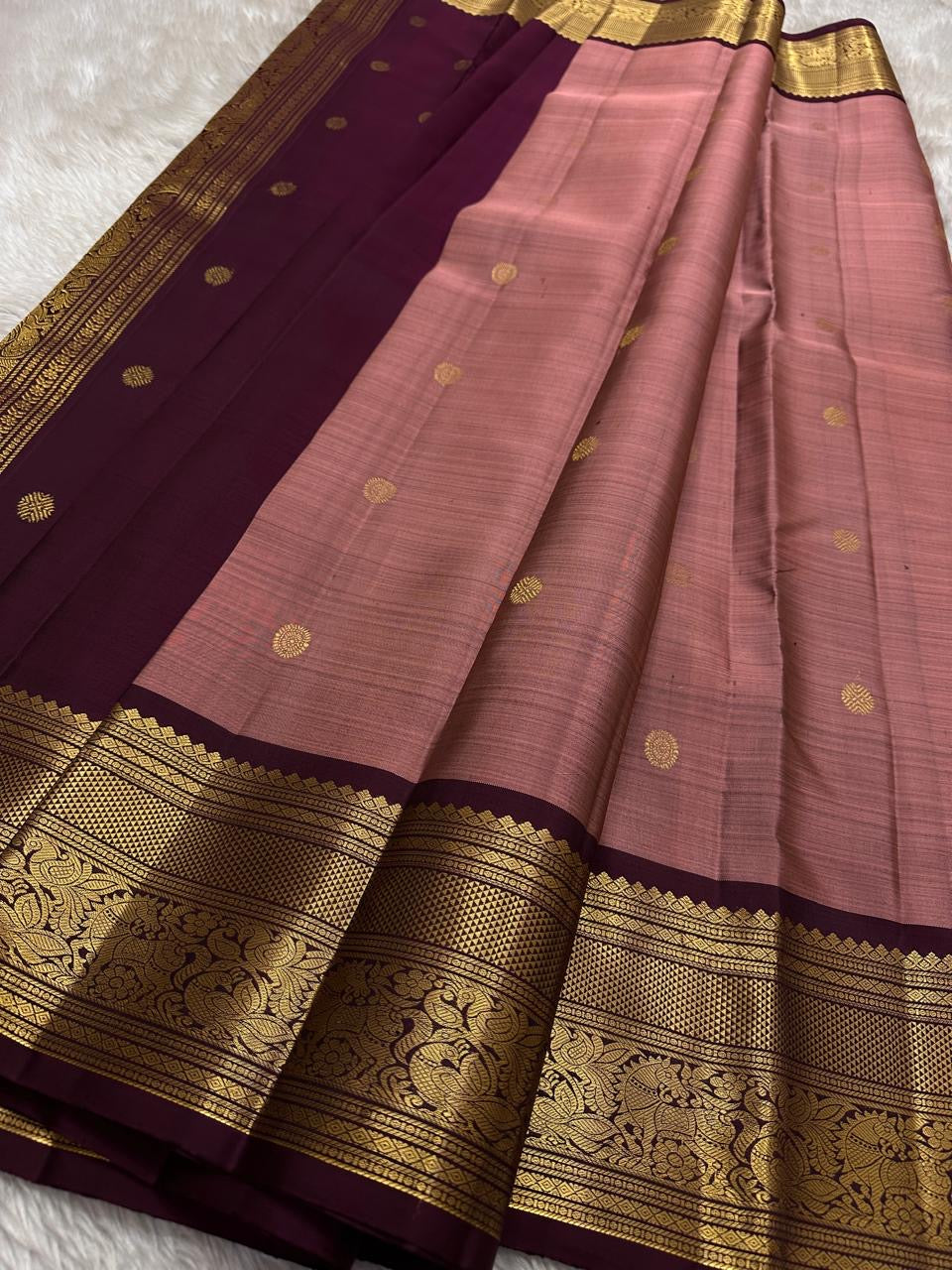 Mauve Buttas – Pure Kanchipuram Silk Saree
Ethereal mauve body adorned with buttas ✨
Borders rich in regal zari with floral and animal artistry 🌿🦚
Grand pallu woven in opulent gold jaal, exuding heritage charm 💫 Silk Mark Certified, delivery in 2 weeks