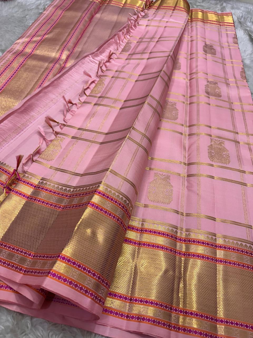 Rose-Quartz Kattam — Kanchipuram Pure Silk  Pastel baby-pink body with windowpane checks (checks )  Minimal zari buttas scattered across the body  Broad gold kaddi borders with pink meenakari accents  Silk Mark Certified | Free Shipping within USA