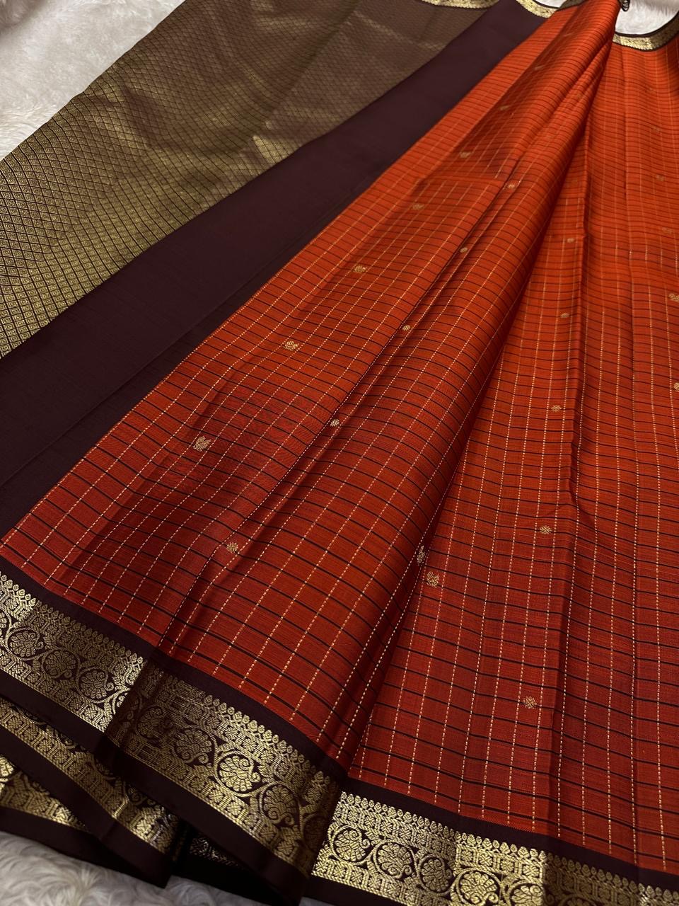 Terracotta Temple – Pure Kanchipuram Silk Saree
Brick red body with fine zari grid checks & golden buttas ✨
Deep coffee-maroon borders and grand diamond-jaal pallu in antique gold.