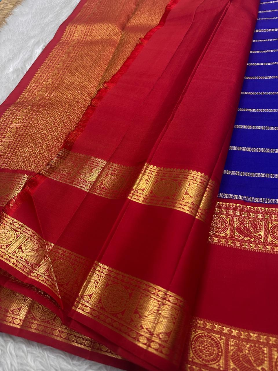Meera – A Living Raga in Kanchipuram Silk: Draped in Crimson and Iconic MS Blue, Adorned with Gold Zari Seer, Muthu Borders, and Peacocks and kamalam , Woven in the Spirit of Classical Grace and Devotion