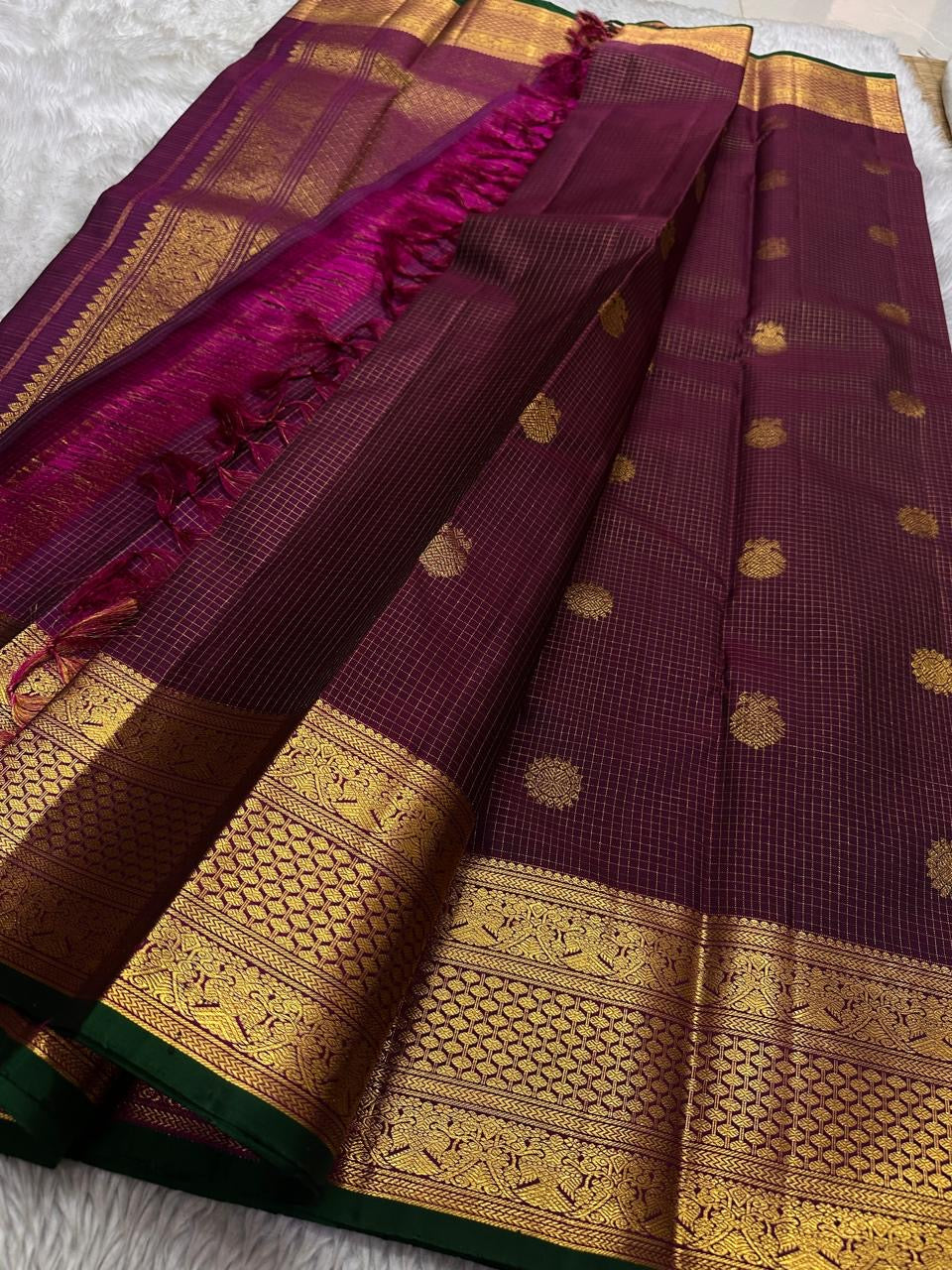 Madhuvanam — Pure Silk Kanchipuram Saree
Brownish-plum body with gold buttas & kattam checks ✨
Antique-gold korvai borders & grand magenta zari pallu 🌸
Silk Mark Certified • Ships in Two Weeks • Free Shipping within USA