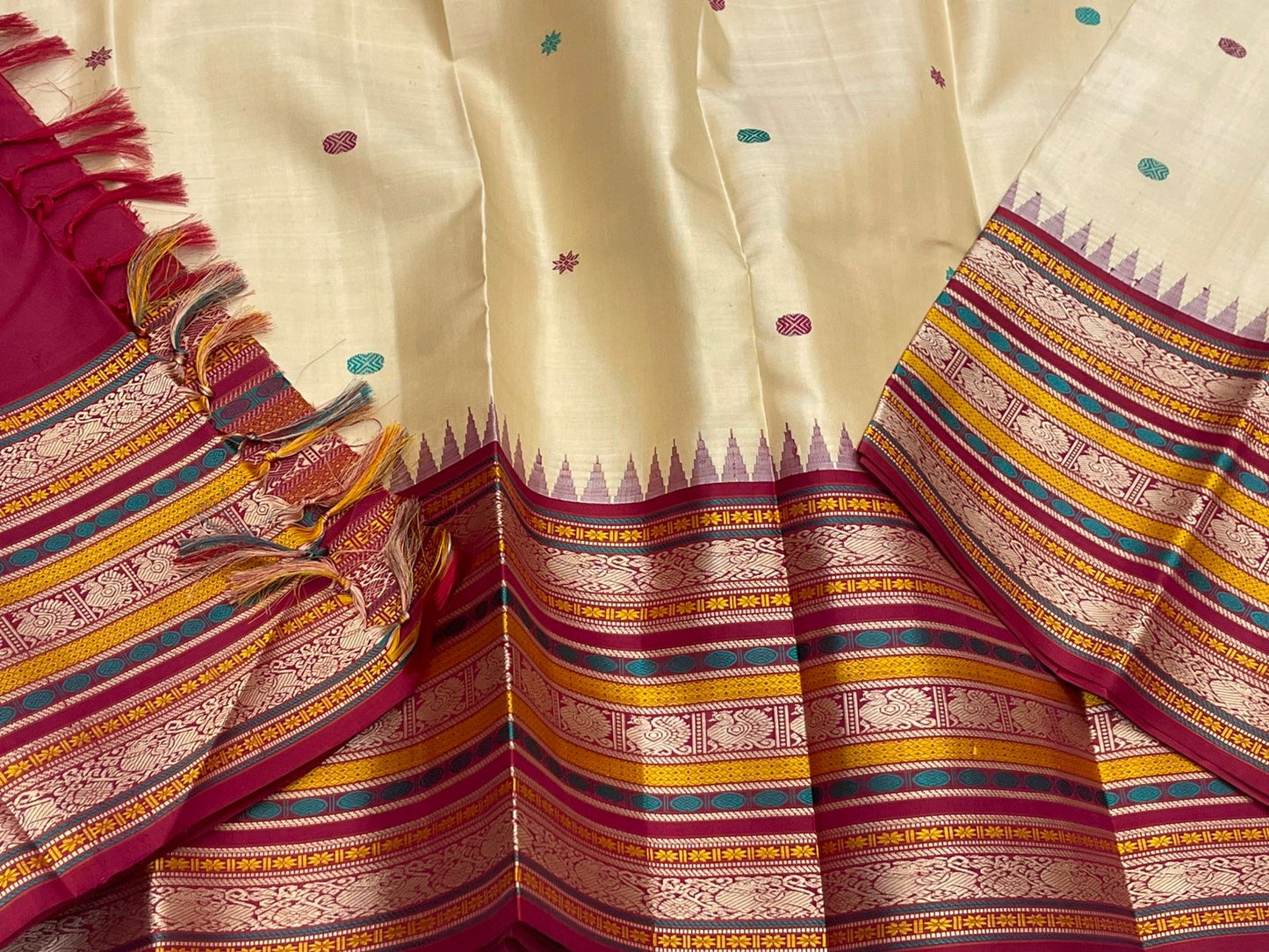 Pari Silk Thread Weaving — Pure Silk Kanchipuram
Ivory body with multi-color silk thread buttas (teal, wine & magenta)
Korvai contrast wine-magenta borders with vintage thread stripe panels
Temple gopuram inner edge & grand pallu in handwoven silk thread