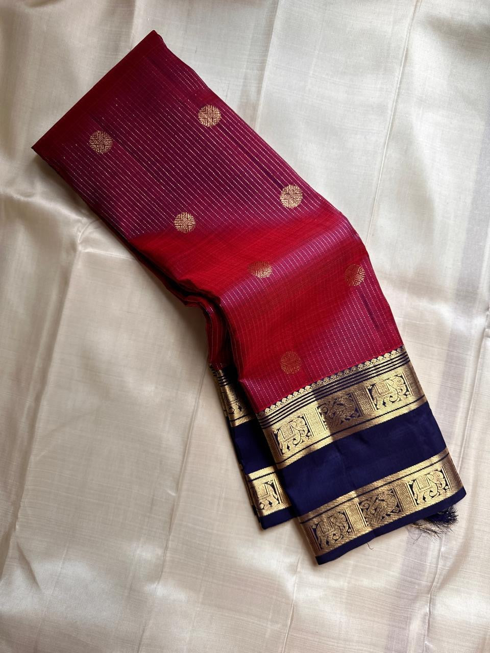 Anuraaga – Neelam
 — Pure Kanchipuram Silk
Vertical Pin-Stripe (Vairaoosi) Body • Gold Coin Buttas
Navy (Neelam) Korvai Border with Elephant Motifs
Diamond-Jaal Brocade Pallu • Running Contrast Blouse
Silk Mark Certified • free shipping in Two Weeks