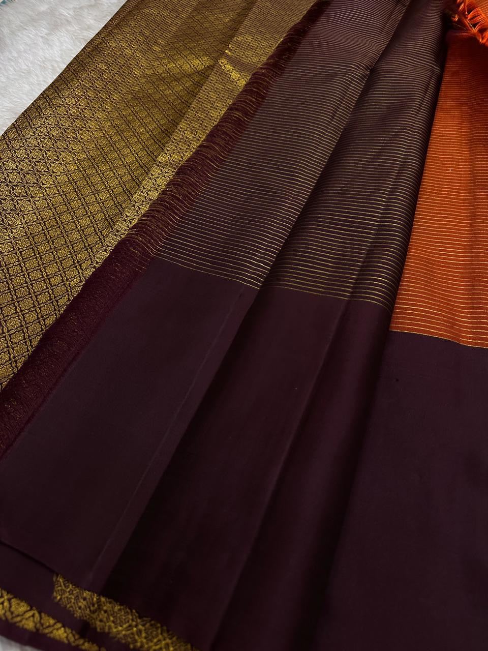 Rust Orange & Wide Broad Silk Korvai – Pure Kanchipuram Silk Saree
Deep wine body adorned with gold ambi buttas for subtle elegance
Contrast rust-orange wide korvai border with podi-kattam micro checks
Grand wine pallu with full-zari diamond jaal