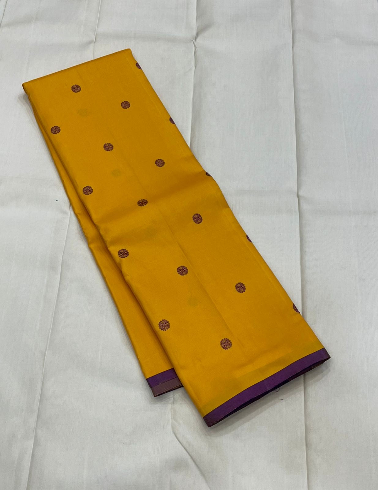 Manjal Vadamalli Chakram – Pure Kanchipuram Silk Saree
Marigold yellow body with purple floral thread buttas
Grand royal purple pallu with gold medallion zari & reku-style stripes
Handwoven Double Warp Weave | Silk Mark Certified | Fall & Pico Done