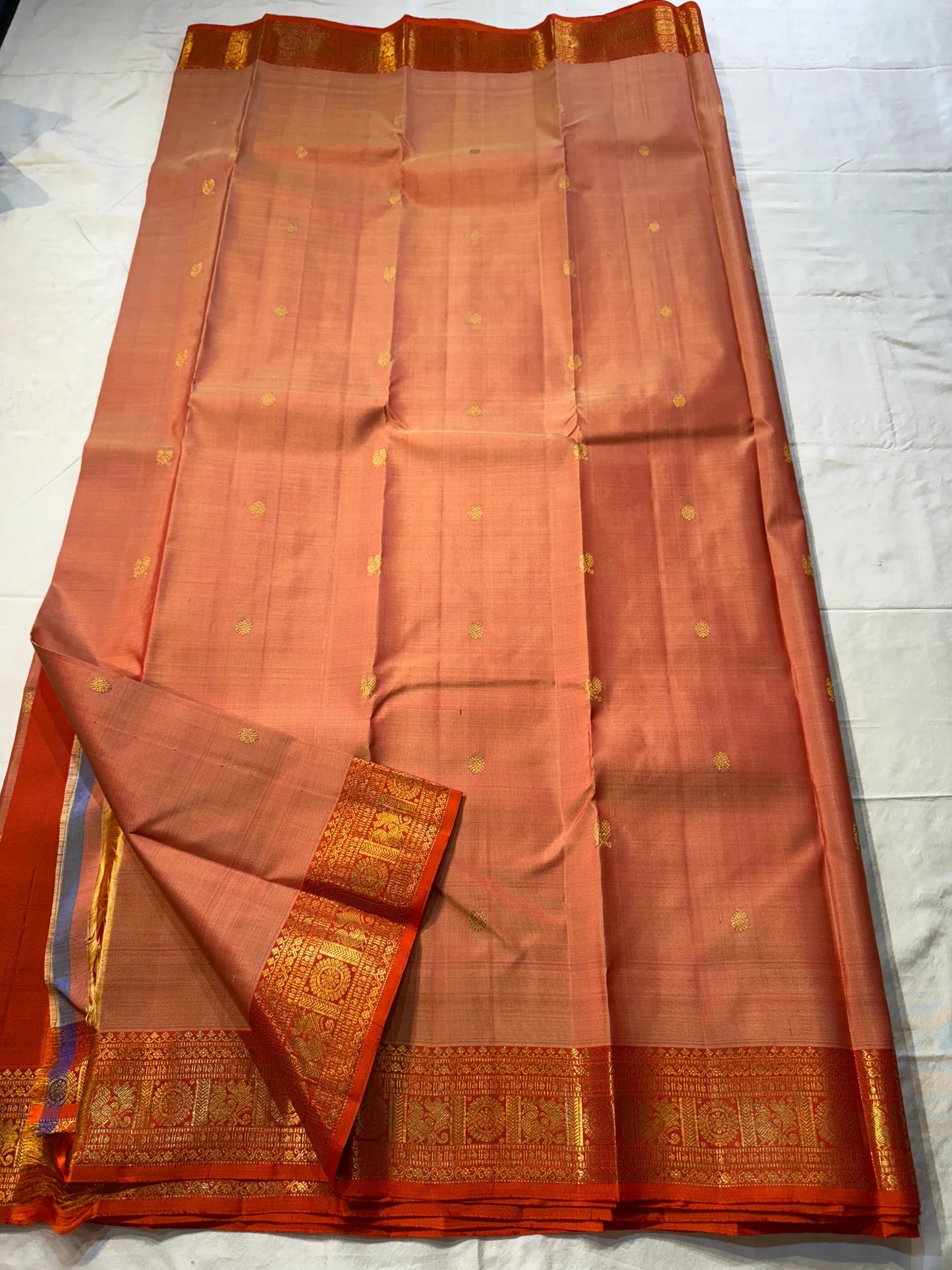 Mandara Peach – Pure Korvai Kanchipuram Silk Saree
Soft peach shot body with dainty gold chakram buttas
Vermilion-orange korvai borders with peacock medallions
Grand kumkumam red pallu with full zari brocade & temple panels
Silk Mark Certified | Free Ship