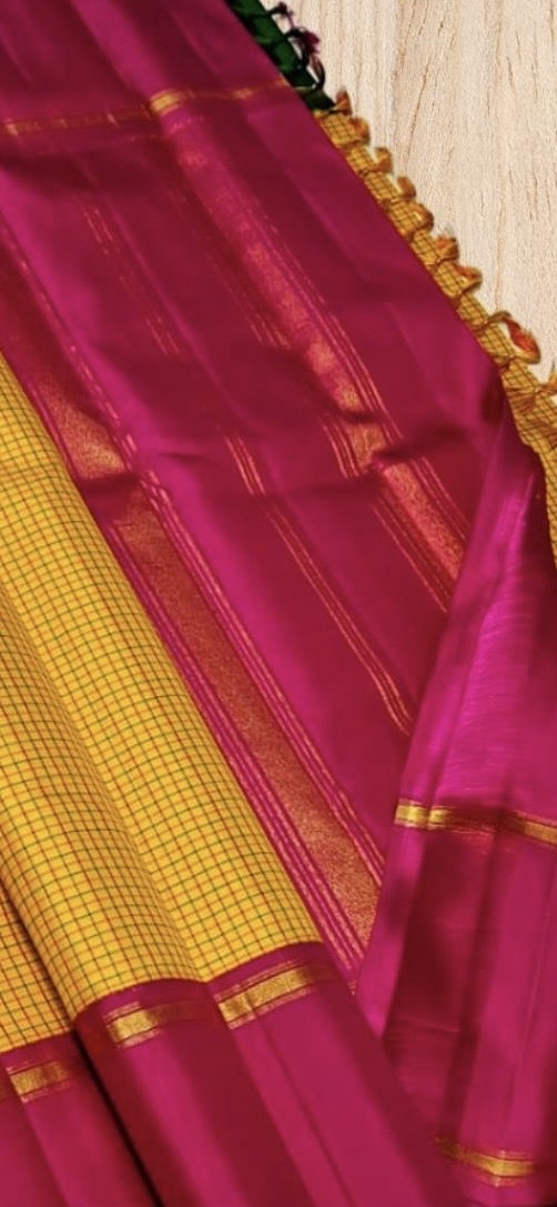 Swarna Kattam Ganga Jamuna — Pure Silk Kanchipuram Saree
Golden mustard kattam checks body • Dual korvai borders in rani pink & emerald green
Rich zari pallu with radiant festive sheen
Contrast emerald blouse with zari selai finish
Silk Mark Certified •