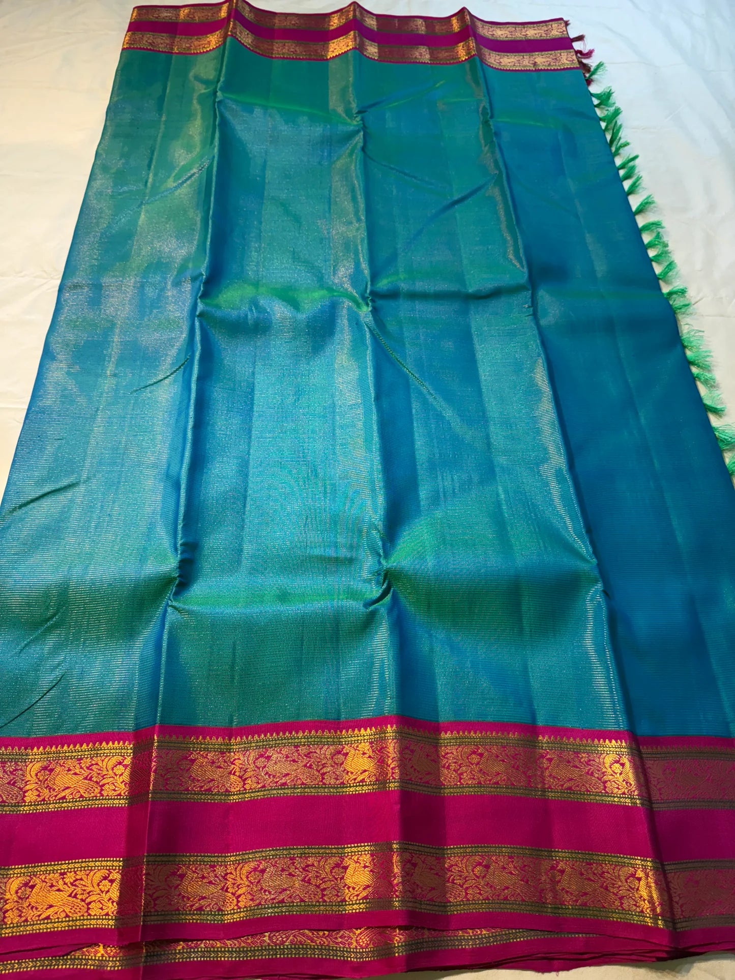 Kavi ✨ – Pure Kanchipuram Silk Saree
Teal Blue Silk Body with Lustrous Shot Weave
Rich Magenta Contrast Border in Gold Zari
Grand Pallu with Intricate Kili (Parrot) Motifs
Magenta Blouse with Matching Zari Border Silk Mark Certified, delivery in 2 weeks
