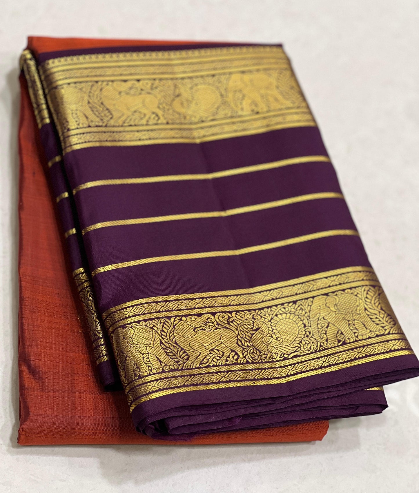 Karpagam – Burnt Orange & Coffee Elegance ✨🪔
A glowing burnt orange body adorned with gold zari peacocks 🦚 and mythical Yazhi 🐉 motifs. The deep coffee border shimmers with Varisaipet geometric zari, while the grand pallu unfolds in panels of Vanasring