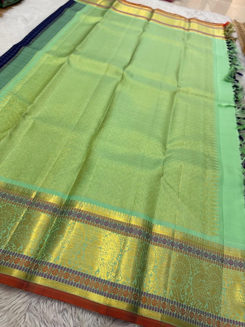 A striking blend of tradition and bold design, this navy blue Kanchipuram silk saree features delicate grid-like checks across the body. What sets it apart is the vibrant mint green and gold zari border, intricately woven with paisley and floral motifs