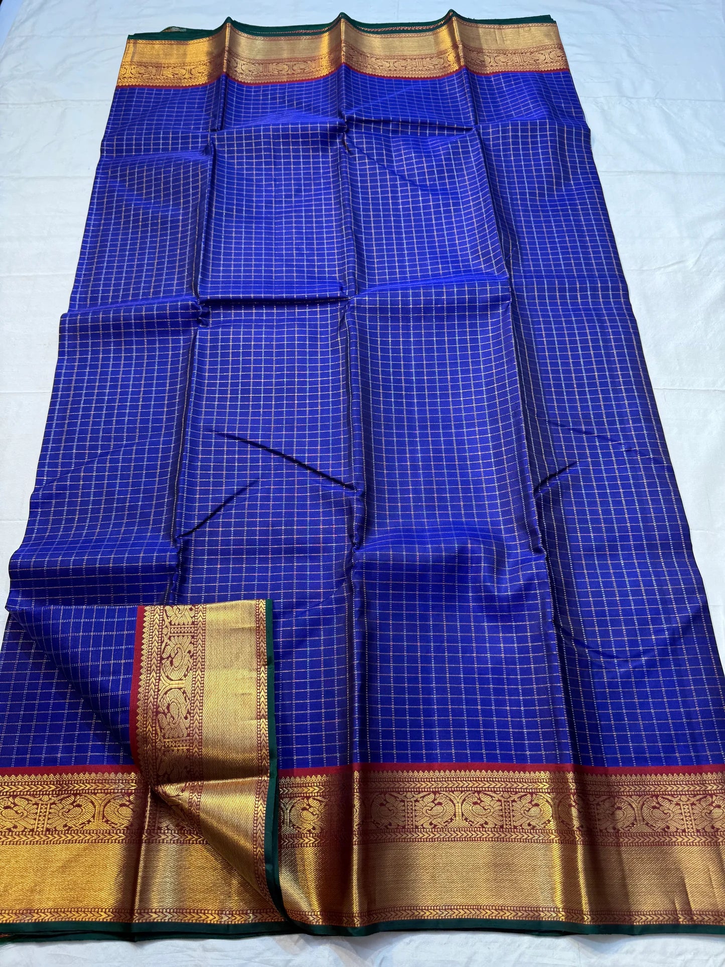 Neela Ratnam — Pure Silk Kanchipuram
• Cobalt-blue kattam checks with antique-gold zari
• Ruby-maroon contrast pallu with grand zari work
• Floral vine borders with bottle-green selvedge
• Silk Mark Certified • Ships in Two Weeks • Free Shipping withi