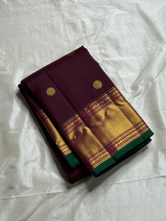Plum & Magenta Round Butta – Pure Kanchipuram Silk Saree
Deep plum body with bold round gold zari buttas
Contrast green selvedge & gold tissue borders with magenta detailing
Grand magenta-pink pallu with full zari diamond jaal & geometric panels
Silk Mark
