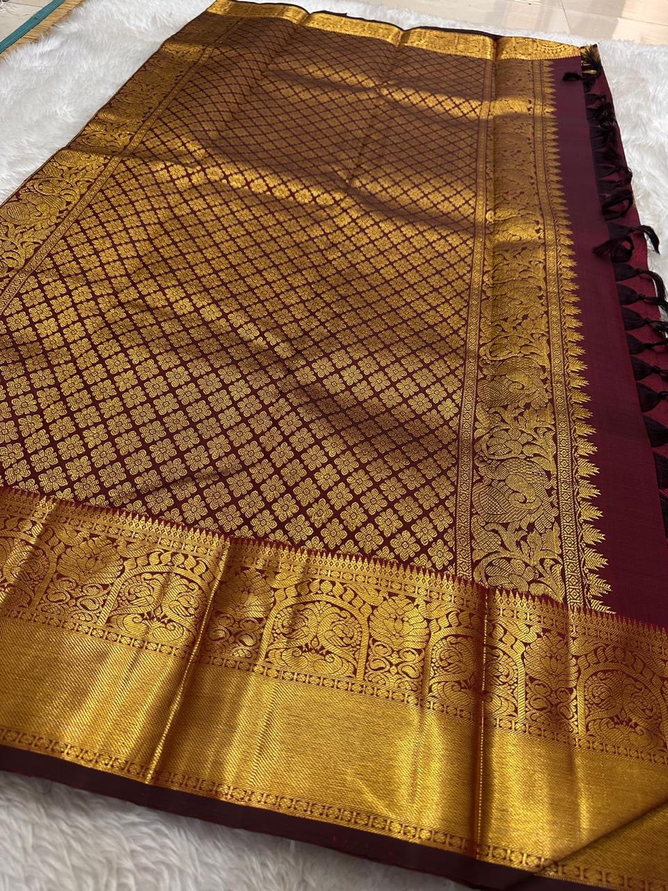 A majestic maroon Kanchipuram silk saree, adorned with intricate golden zari featuring the mythicalYazhi (Yali ) motifs—a symbol of divine strength and protection in Hindu mythology. The grand temple-style gold border adds depth and regality, making this