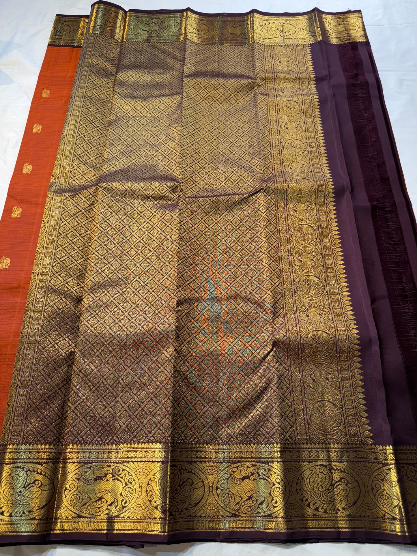 Rust Orange & Wine Korvai – Pure Kanchipuram Silk Saree
Burnt rust-orange shot body with dainty gold paisley buttas
Deep wine korvai borders in antique gold—Annapakshi & Yaali medallions
Grand wine pallu with full-zari jaal & temple panels
Silk Mark