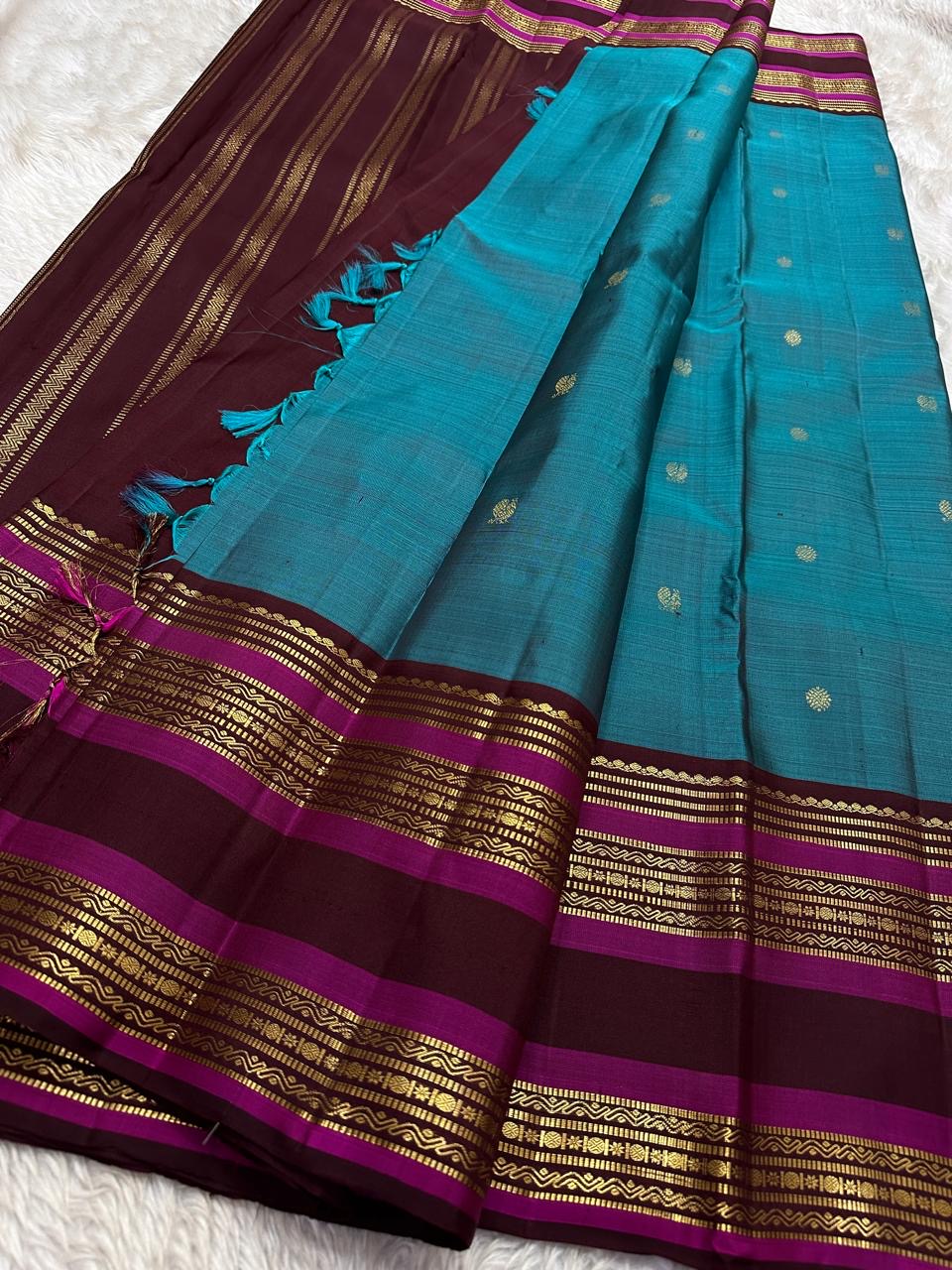 Neelam Jamuna – Pure Kanchipuram Silk Saree
A teal body adorned with glowing zari buttas.
Wine korvai border detailed with antique-gold.
A majestic jamuna pallu rich in brocade artistry.
Silk Mark Certified, delivery in 2 weeks