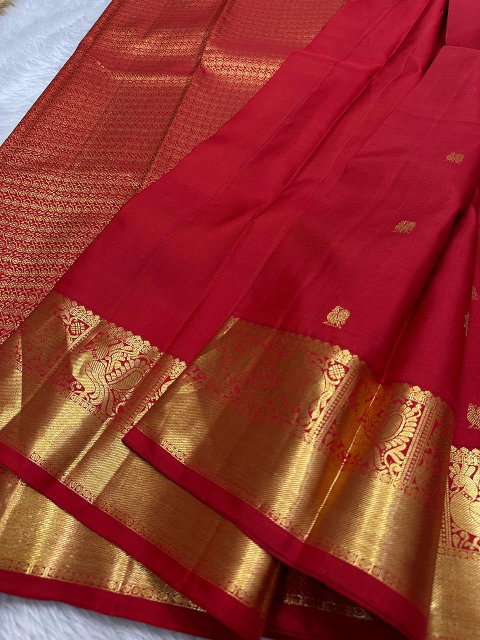 Dia ✨ – Chilli Red Pure Kanchipuram Silk Saree
Allover Gold Zari Floral Buttas on Body
Broad Elephant–Peacock (Gaja–Mayil) Zari Panel Border
Rich Red & Gold Brocade Pallu with Intricate Weaves
Silk Mark Certified | Fall & Pico Done | Blouse Stitching $30