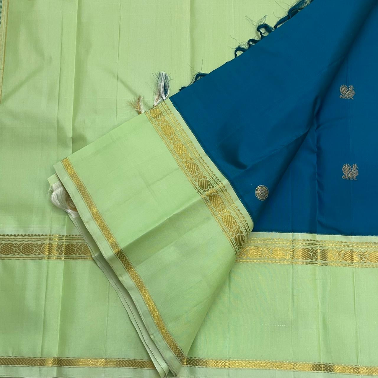 Vasantha Neelam — Teal Korvai Kanchipuram Pure Silk Saree
Peacock-blue body with gold muthu buttas · Mint-pistachio korvai border & pallū
Handloom Kanchipuram • Contrast running blouse included
Silk Mark Certified
Free Shipping within USA, 2 weeks
