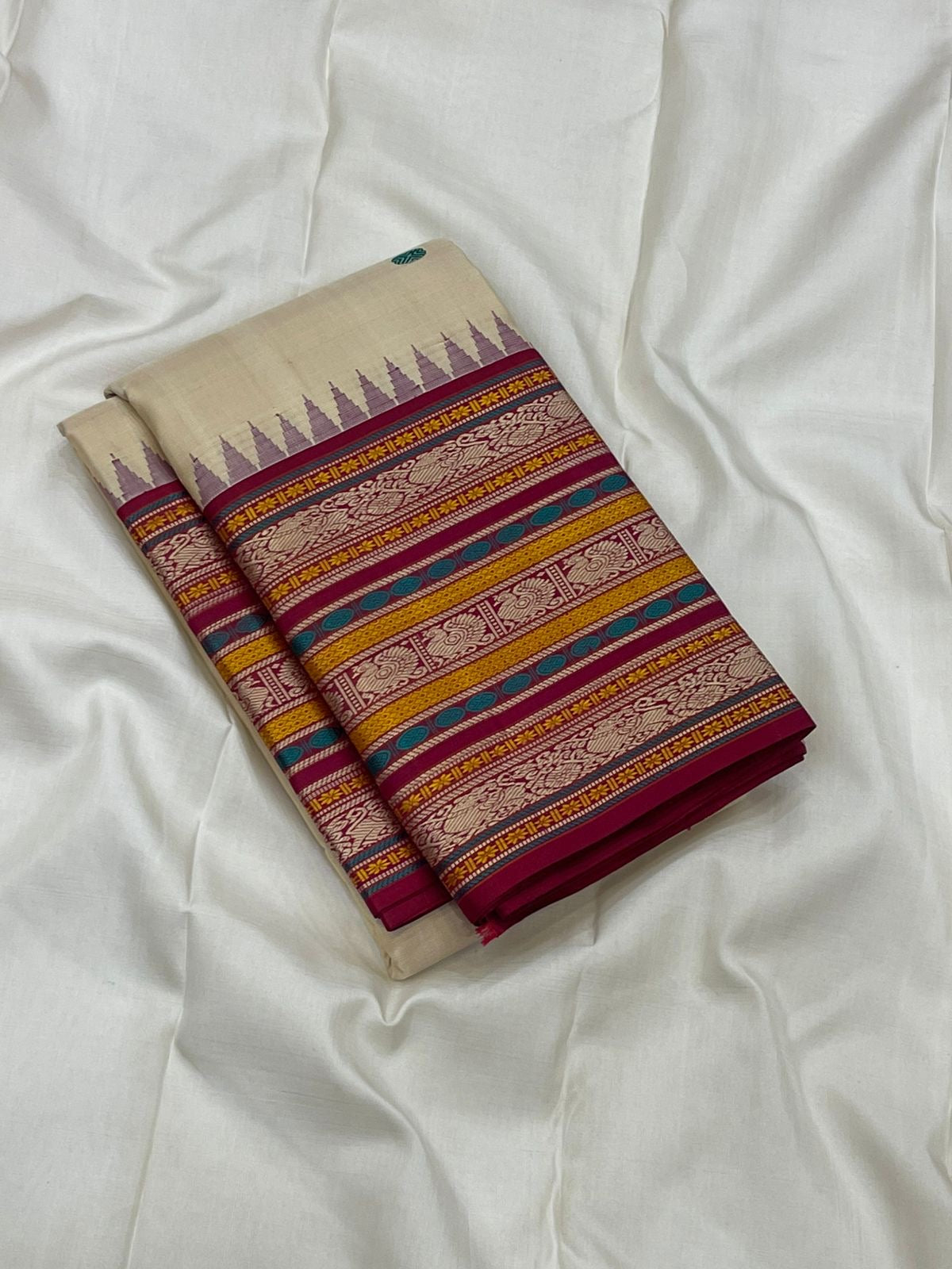 Pari Silk Thread Weaving — Pure Silk Kanchipuram
Ivory body with multi-color silk thread buttas (teal, wine & magenta)
Korvai contrast wine-magenta borders with vintage thread stripe panels
Temple gopuram inner edge & grand pallu in handwoven silk thread