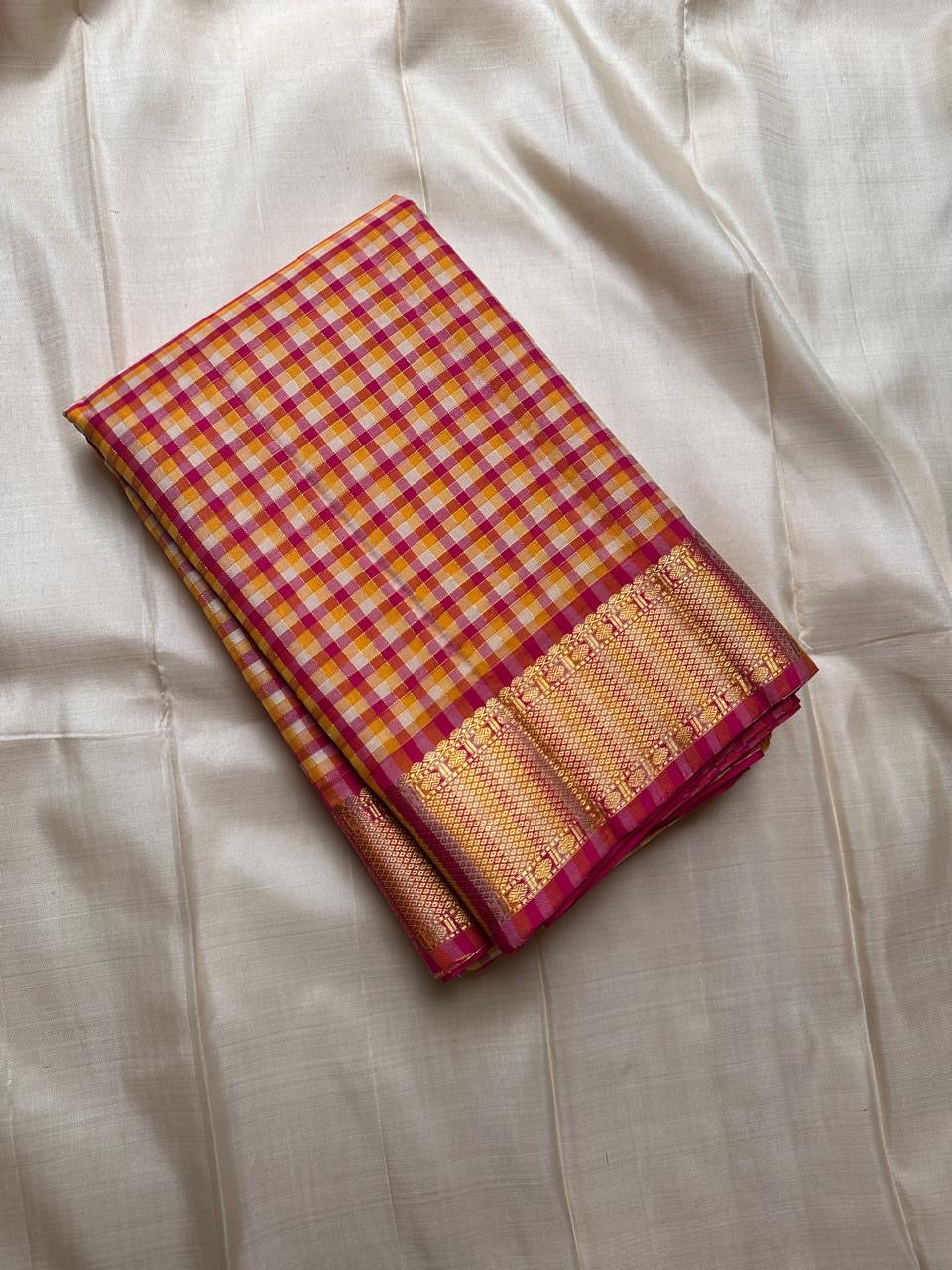 A classic Kanchipuram in Pattani Kattam checks with pink, magenta, mustard, and cream.
Finished with a contrast pink border and pallu.
Paisley and chakram motifs in a graceful grid add timeless charm.