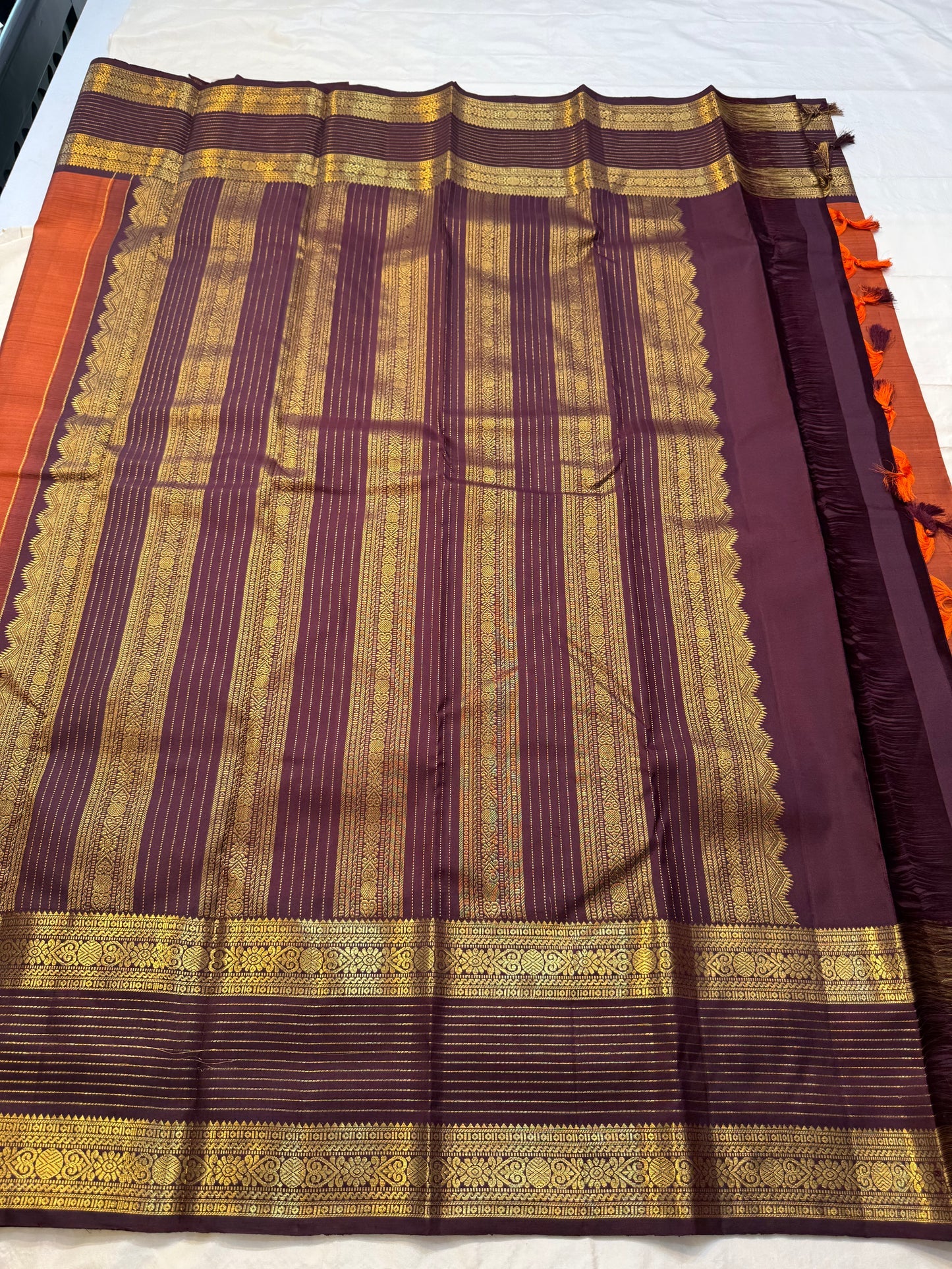 🧡 
Swarnamala — Korvai Kanchipuram Pure Silk
Rust-orange body with radiant gold chakram buttas
Deep purple korvai borders with rich zari detailing
Striped zari brocade pallu with temple-inspired motifs
Silk Mark Certified • Free Shipping within USA