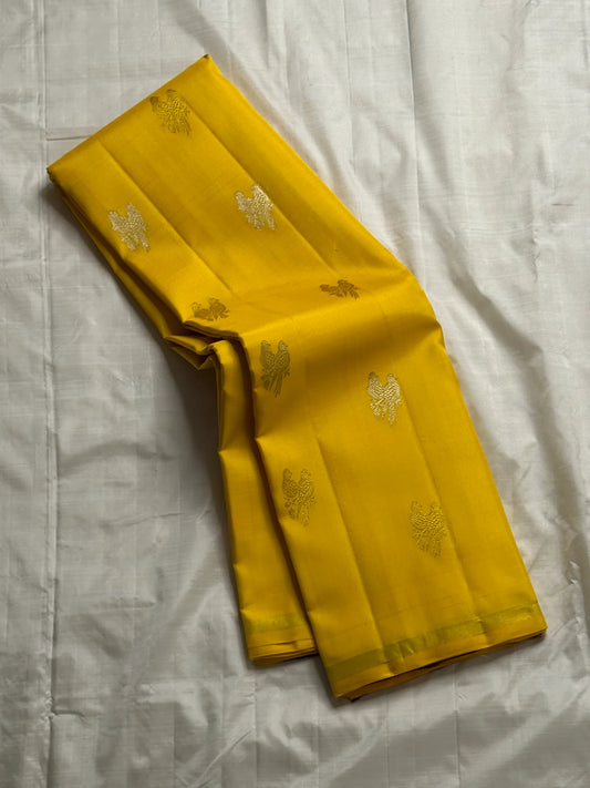Kanaka Mayuri — Pure Silk Kanchipuram Saree
Haldi / Marigold Yellow with Silver-Zari Peacock Buttas ✨
Minimal Self Borders • Contrast Plum Brocade Pallu 💜
Handwoven in Pure Mulberry Silk | Silk Mark Certified ✅
Ships in Two Weeks Free | Idam Living