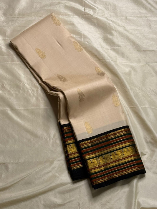 Sandal Annam Varisaipet – Korvai Kanchipuram Silk Saree
Pure handloom silk | Sandal-beige body with gold paisley buttas
Black korvai border with annam panels, varisaipet stripes & muthuseer rows
Coordinated dark zari-brocade pallu | Contrast black blouse