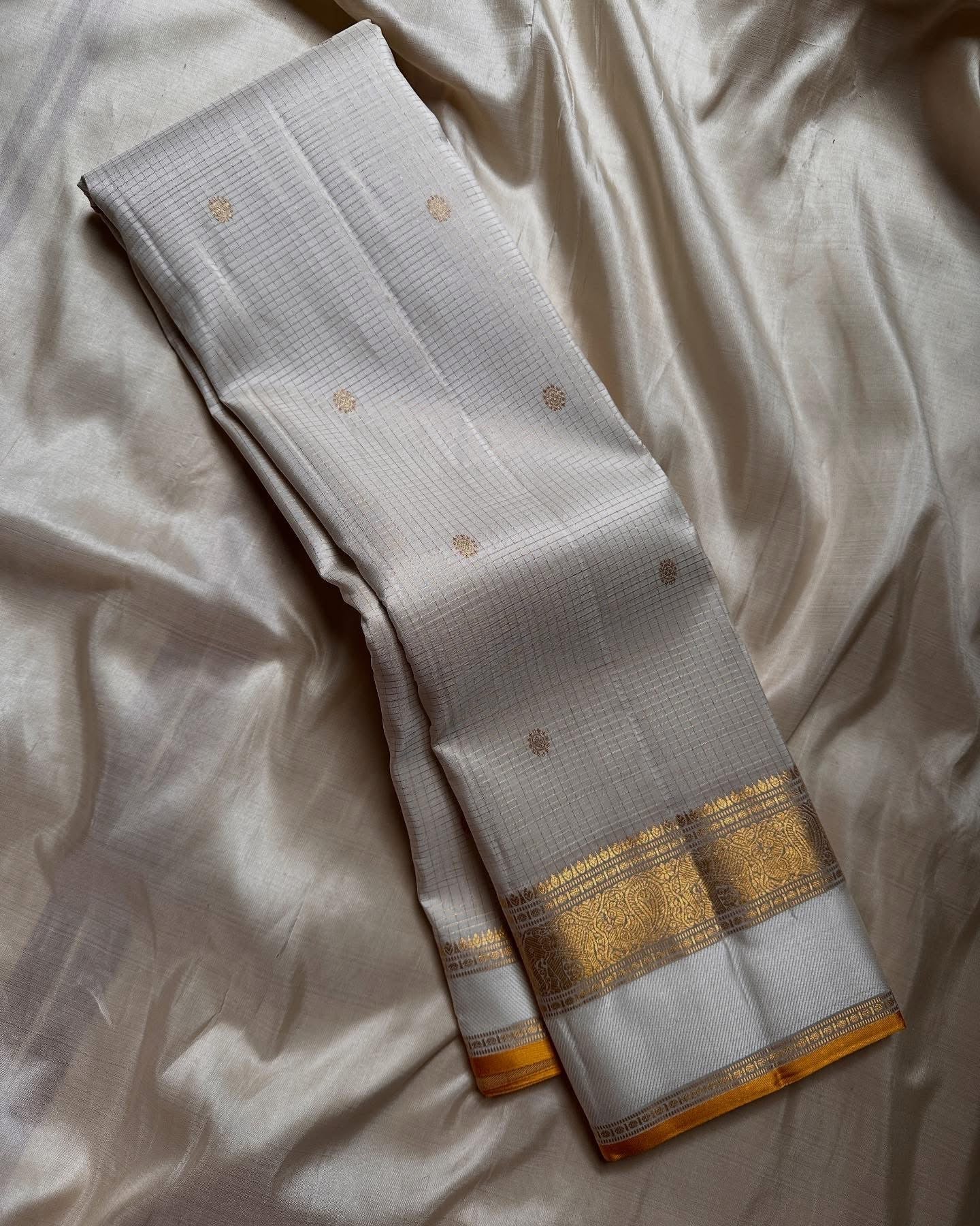 Kiran ivory whiteb oosi kattam ✨ – ivory and gold Kanchipuram Pure Silk Saree
Korvai Gold Zari Border with Elephant & Floral Motifs
Body Woven in Zari Kattam Checks with Scattered Gold Buttas
Grand Zari Brocade Pallu | Silk Mark Certified |