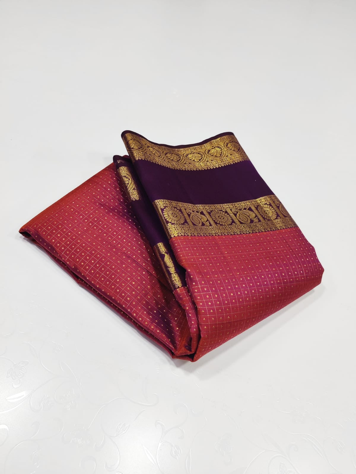 Crimson Amethyst – Pure Kanchipuram Silk Saree
Radiant crimson red body woven with delicate gold kattam checks at Iran buttas ✨
Paired with rich amethyst purple korvai borders in ornate zari
Grand brocade pallu Silk Mark Certified, delivery in 2 weeks