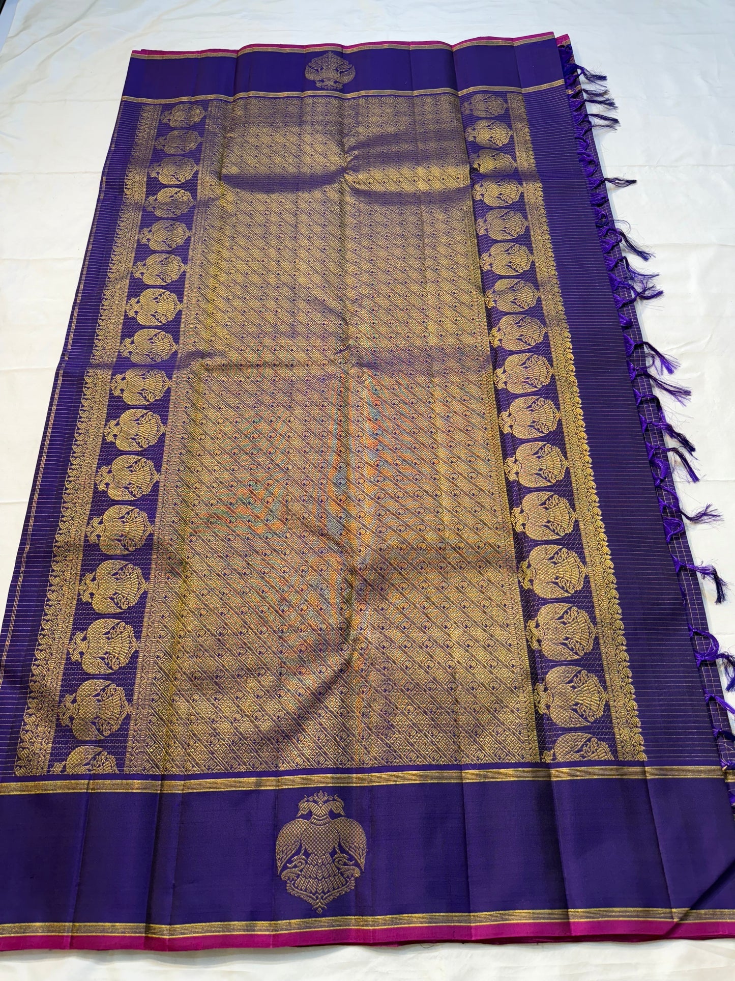 Vadamalli Gandaberunda Kattam — Pure Silk Kanchipuram Saree
Royal purple body with fine kattam checks & zari mankolam buttas, adorned with grand Gandaberunda borders and rich diamond brocade pallu with pink selvedge.
Silk Mark Certified ✅ | Fall & Pico