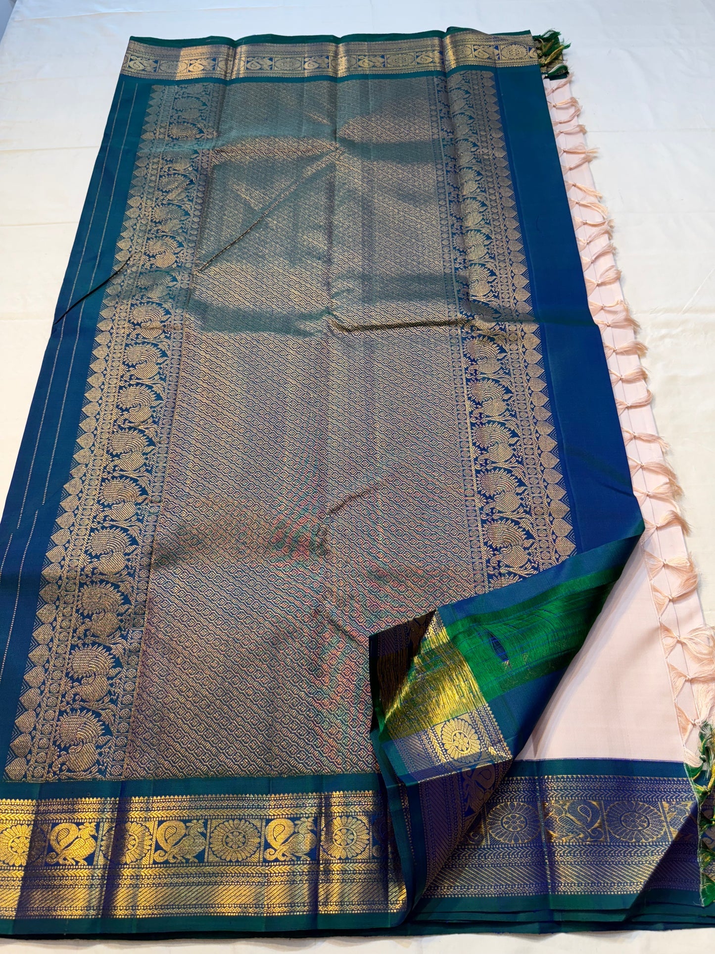 Mayilkazhuthu Shwetham — Pure Kanchipuram Silk Saree
Soft Ivory-Blush Body with Gold Zari Buttas & Peacock Blue-Green Border
Silk Mark Certified • Free Shipping within USA • Ships in Two Weeks