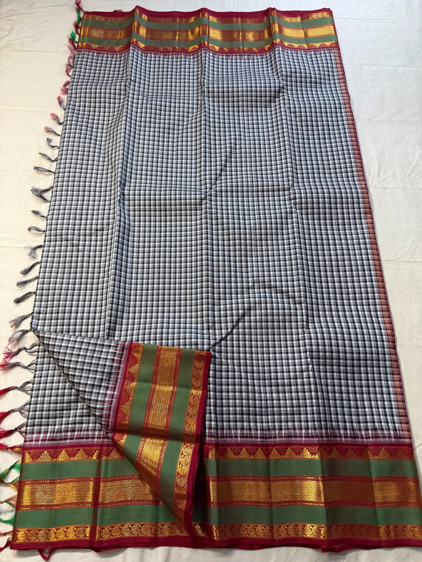 Onyx Plaid – Pure Kanchipuram Silk Saree
Black & Ivory Micro-Checks Body (Kattam) ✨
Parrot-Green Korvai Border with Gold Zari
Crimson Pallu with Orange Panel & Kaddi Stripes
Silk Mark Certified, delivery in 2 weeks