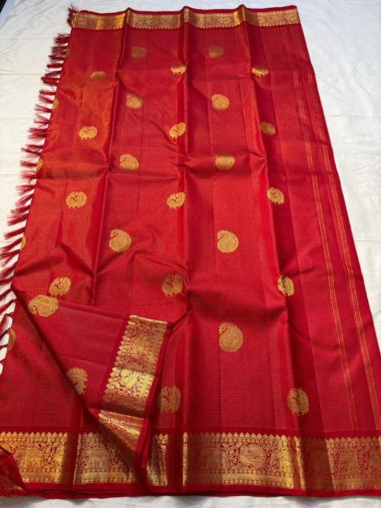 Thilakam Red Vairaoosi — Pure Silk Kanchipuram Saree
Radiant vermilion-red body with gold vairaoosi pinstripes and paisley buttas, paired with a fiery orange-red brocade pallu and grand peacock–elephant zari border ✨
Silk Mark Certified • Fall & Pico Done