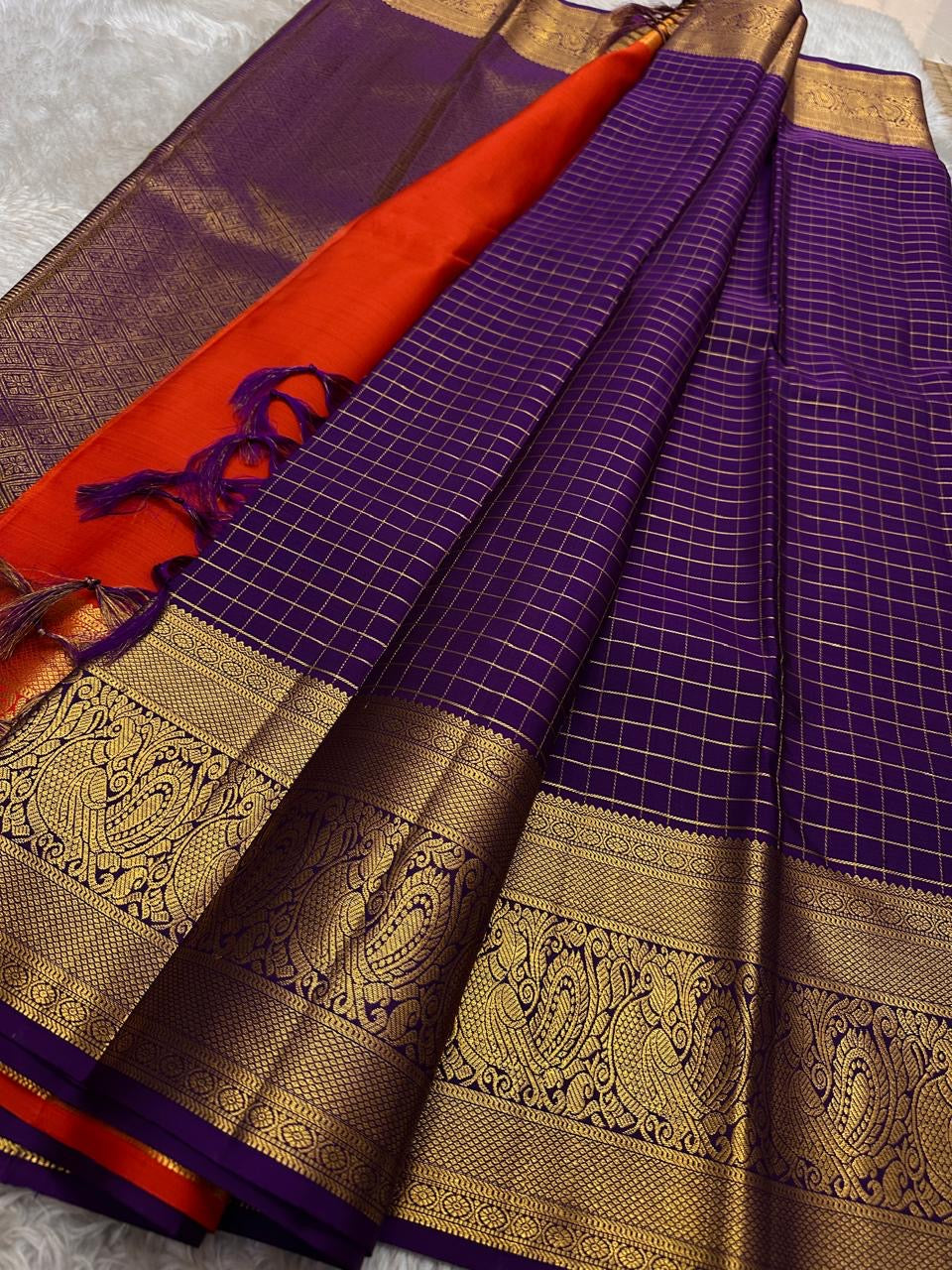 Aubergine Amber Kattam – Pure Kanchipuram Silk Saree
Deep Aubergine Purple Body with Gold Kattam Checks
Grand Zari Borders with Majestic Peacock Motifs
Contrast Amber-Orange Pallu with Rich Zari Detailing
Silk Mark Certified | ships in two weeks