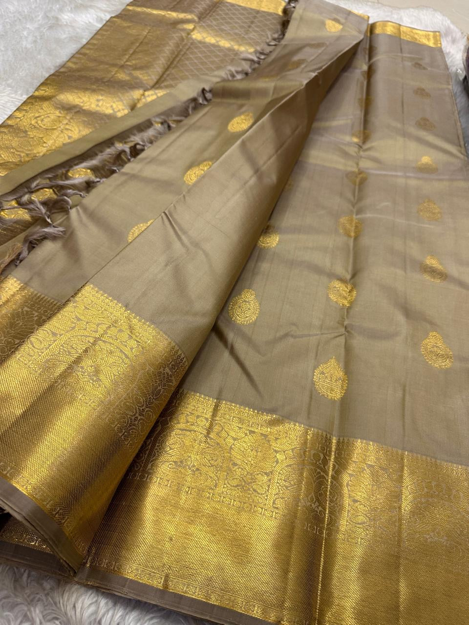 Chiku Orchard – Pure Kanchipuram Silk Saree
Elegant Chiku (Taupe) Body with Gold Paisley Buttas
Rich Antique Gold Zari Borders with Floral Motifs
Grand Gold Zari Pallu with Traditional Kattam Design
Silk Mark Certified | Ready to Ship | ships in two weeks