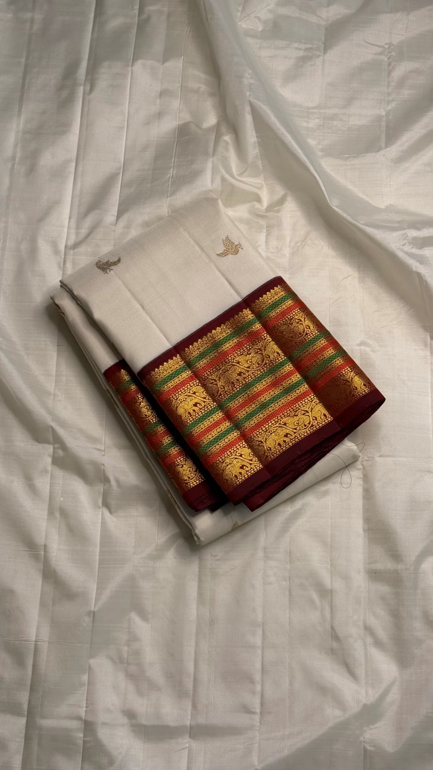Parakkum Kili — Ivory Pure Silk Kanchipuram
Ivory body with fine zari coin buttas ✨
Rust-orange korvai borders with mayil & temple motifs 🌸
Grand rust-orange zari brocade pallu with tassels 🪔
Silk Mark Certified • Free Shipping USA • Ships in Two Weeks