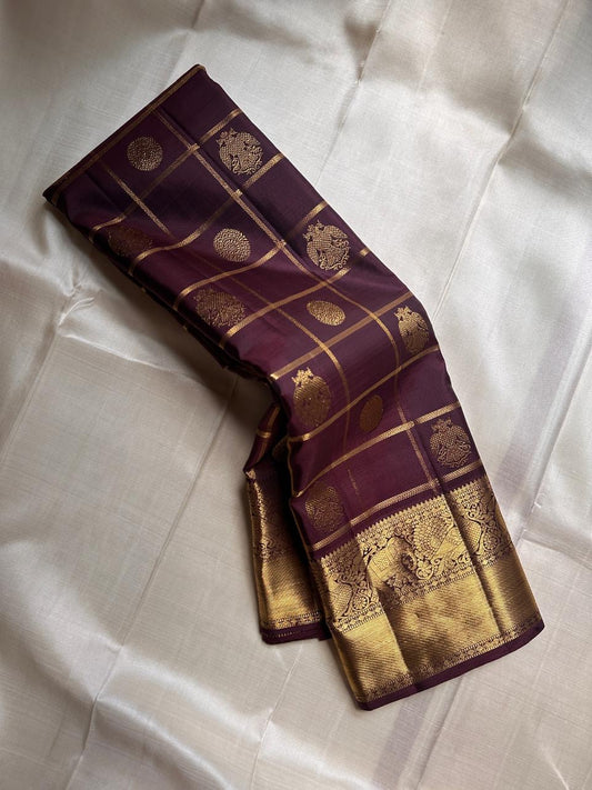 Folded view of plum Gandaberunda zari kattam Kanchipuram silk saree with rich gold elephant border on ivory base.
