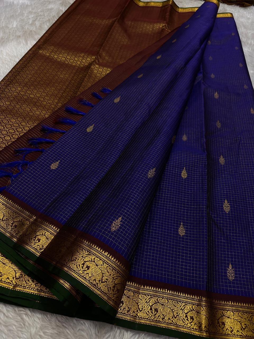 Midnight Oosikattam ✨ – Pure Kanchipuram Silk Saree
Deep Midnight Blue Body in Oosi Zari Kattam with Leaf Buttas
Maroon Korvai Border with Green Selvedge & Elephant Motifs
Opulent Maroon Pallu with Intricate Gold Zari Brocade
Silk Mark Certified |